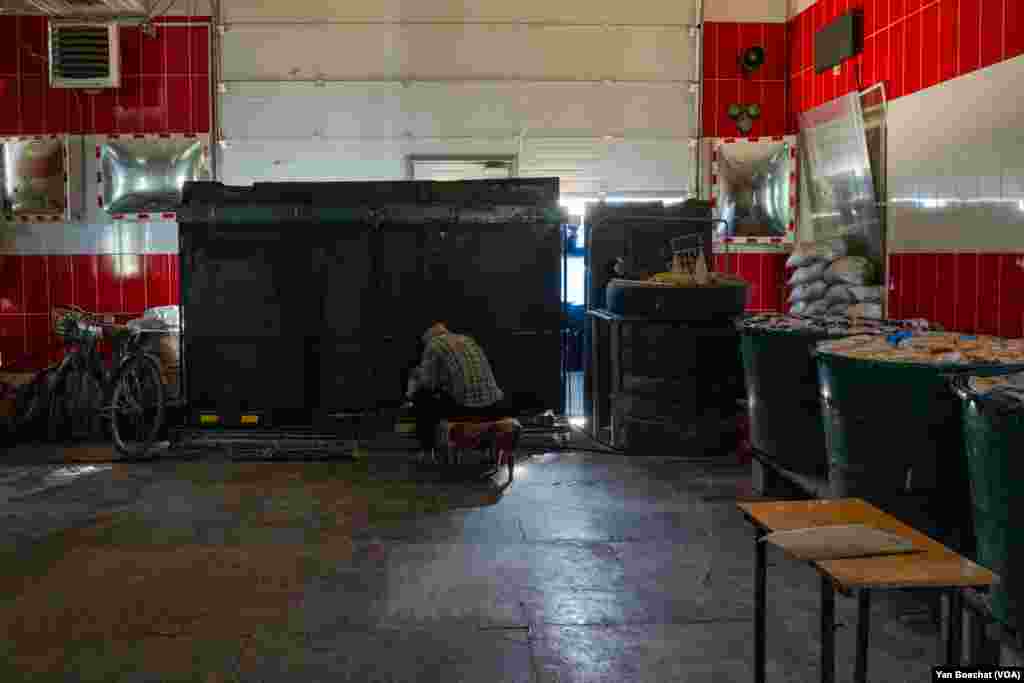 A man cooks on an improvised stove inside the former Velyka Novosilka, Ukraine firehouse, on Aug. 23, 2023 