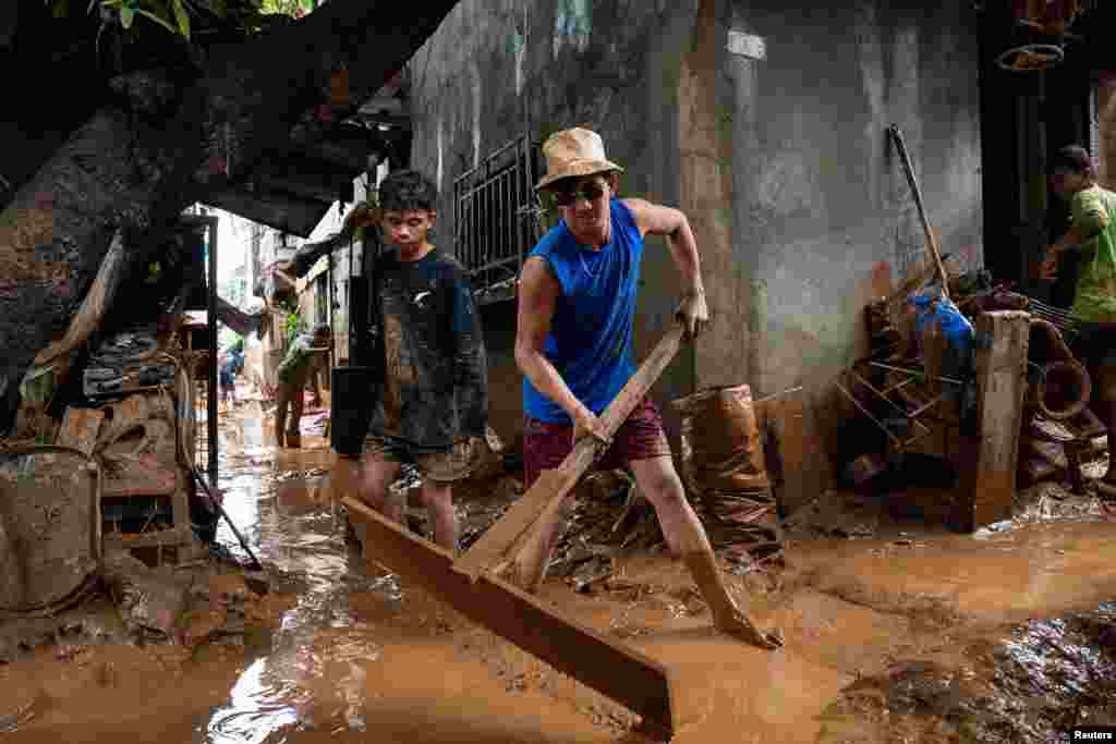 A man sweeps the mud off the alley following the floods brought by Typhoon Gaemi, in San Mateo town, Rizal province, Philippines, July 25, 2024.