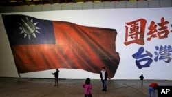 Sekelompok anak terlihat bermain di depan gambar bendera nasional Taiwan di Taipei, Taiwan, Sabtu, 13 Januari 2024. (Foto: AP)