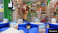 Seorang pedagang menata karung beras di kiosnya, di sebuah pasar tradisional di Bekasi, pinggiran Jakarta, 1 Maret 2024. (REUTERS/Ajeng Dinar Ulfiana)