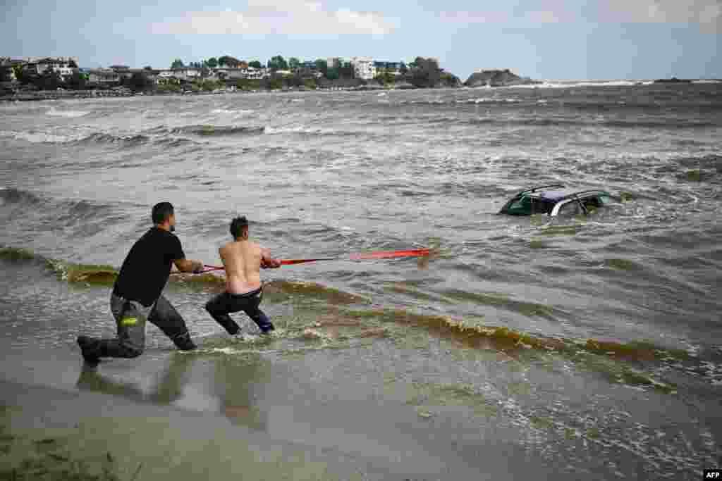 People pull ashore a car submerged in the sea at the Arapia camping site near Tsarevo, along the Bulgarian Black Sea coast.&nbsp;Heavy rain and thunderstorms that began Monday are causing rivers to overflow, damaging bridges and causing more than 100 seaside holidaymakers and locals to be evacuated to safer areas.