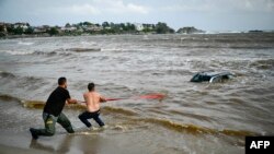 People pull ashore a car submerged in the sea at the Arapia camping site near Tsarevo, along the Bulgarian Black Sea coast after heavy rains and thunderstorms caused flooding. (Photo by Nikolay DOYCHINOV / AFP)