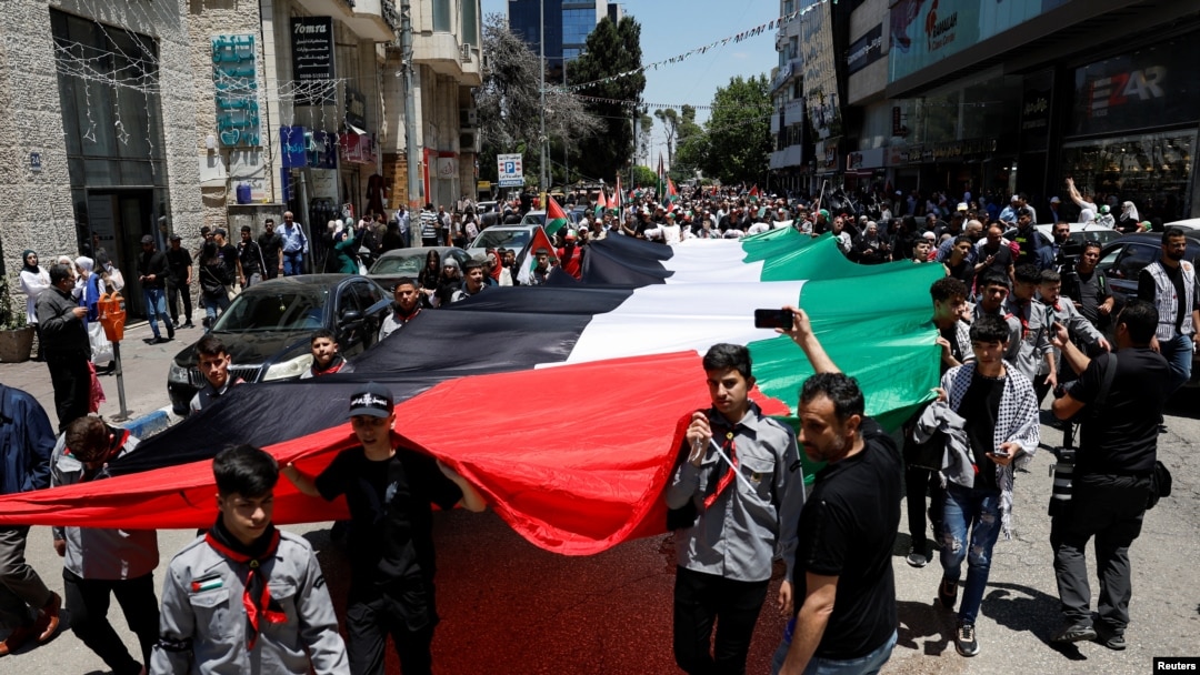 Ribuan warga Palestina mengarak bendera Palestina raksasa saat ambil bagian dalam protes untuk memperingati 76 tahun Nakba, "bencana" perampasan massal tanah mereka dalam perang tahun 1948 di kota Ramallah, Tepi Barat yang diduduki Israel, Rabu 15 Mei 2024.