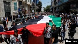 Ribuan warga Palestina mengarak bendera Palestina raksasa saat ambil bagian dalam protes untuk memperingati 76 tahun Nakba, "bencana" perampasan massal tanah mereka dalam perang tahun 1948 di kota Ramallah, Tepi Barat yang diduduki Israel, Rabu 15 Mei 2024.