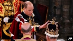 Britain's Prince William touches Saint Edward's Crown on King Charles III's head during his coronation ceremony in Westminster Abbey, London, May 6, 2023.