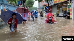 People make their way through a flooded street after heavy rains in Hanoi, Vietnam, Sept. 28, 2023.