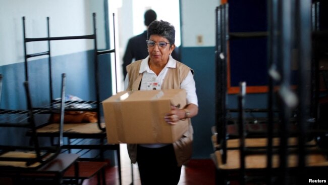 Una funcionaria del Tribunal Superior de Justicia Electoral de Paraguay traslada una caja que contiene una máquina de votación a una escuela pública, que será un centro de votación, un día antes de las elecciones presidenciales, en Asunción, Paraguay, 29 de abril de 2023. REUTERS/Agustin Marcarian