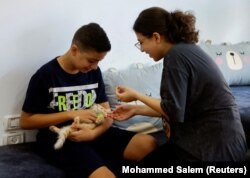 Warga Palestina bermain dengan kucing di "MEOW Cat Cafe" di Kota Gaza, 20 Agustus 2023. (Foto: REUTERS/Mohammed Salem)