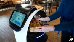 Seorang pelanggan menerima makanan yang diantarkan oleh robot BellaBot di restoran Noodle Topia di Madison Heights, Michigan, 20 Maret 2023. (AP/Carlos Osorio)