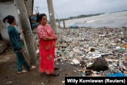 Solikah, 58, dan Cartini, 35, mengamati sampah, sebagian besar plastik dan sampah rumah tangga, yang menutupi pantai di lingkungan mereka di desa nelayan Teluk, Pandeglang, Banten, Maret 15, 2024. (Foto: REUTERS/Willy Kurniawan)