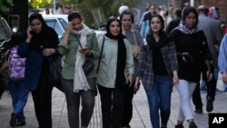 FILE - Iranian women, some without wearing their mandatory headscarves, walk in Tehran on Sept. 9, 2023. Iran has arrested four people, accusing them of giving a foreign-based broadcaster video of an argument between a Shiite cleric and a woman not wearing a headscarf.