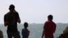 Palestinian youths stand on a jetty in Gaza City with a view of navy vessels as part of a humanitarian 'maritime corridor' announced by US Central Command (CENTCOM) on May 17, 2024.