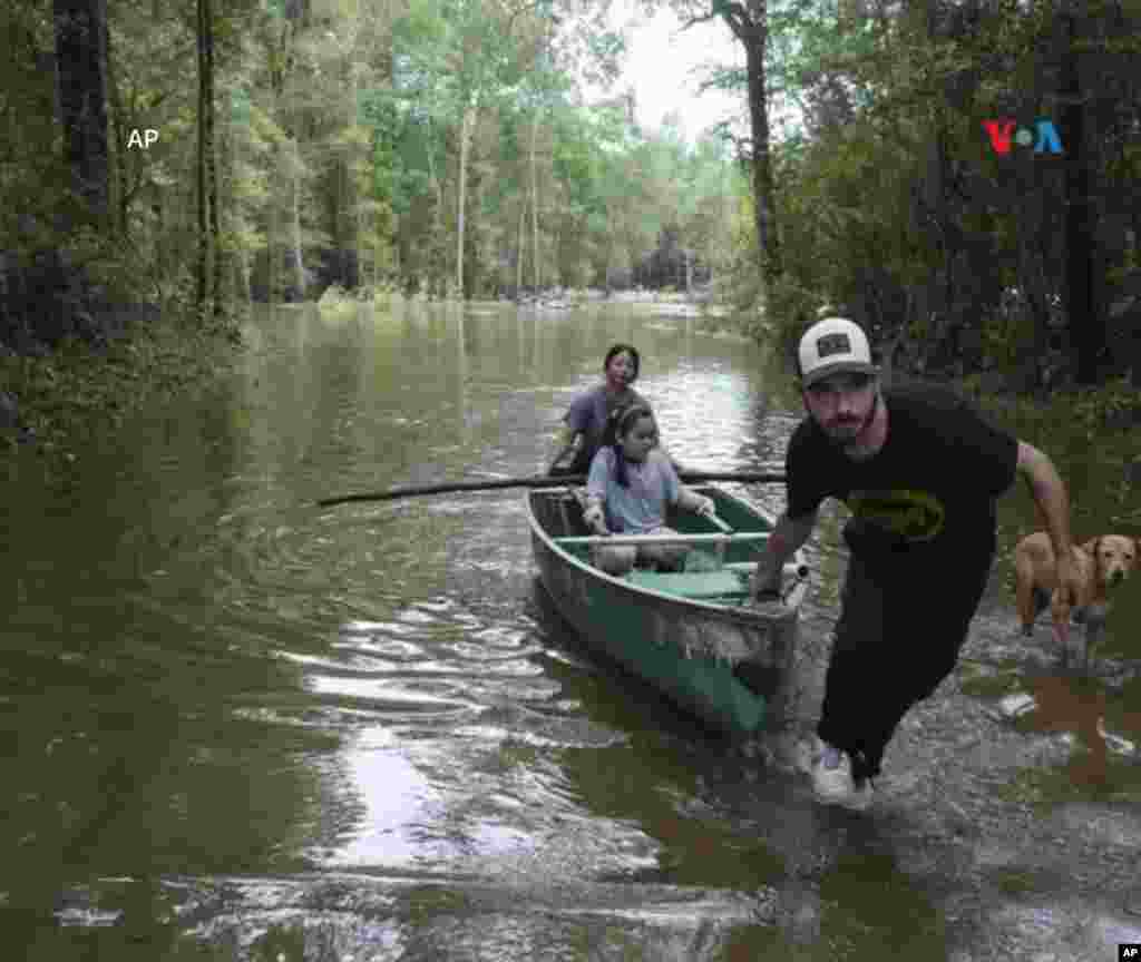 Álvaro Treviño hala una canoa con Jennifer Tellez y Ailyn, de 8 años, después de revisar su casa el domingo 5 de mayo de 2024 en Spendora, Texas.