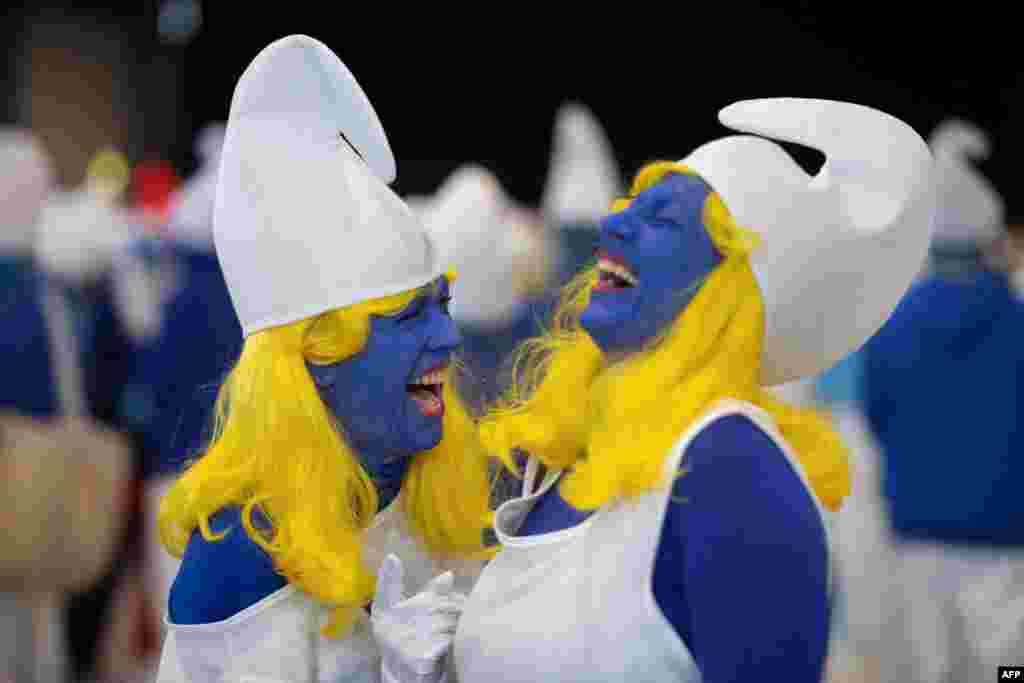 Women dressed as Smurfs, a Belgian comic franchise centered on a fictional colony of small, blue, human-like creatures who live in mushroom-shaped houses in the forest, share a light moment in a world record gathering of Smurfs in Landerneau, western France, March 25, 2023.