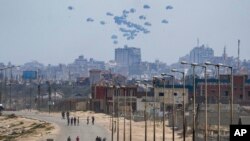 资料照片: 2024年4月30日从加沙中部看到一架飞机在加沙地带北部空投人道主义援助物资