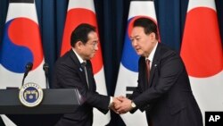 韩国总统尹锡悦（右）与日本首相岸田文雄在首尔总统府会晤后举行的联合记者会上握手。（2023年5月7日）