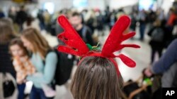 Cheryl Grunwarld, wearing antlers, waits for her baggage at the Charlotte Douglas International Airport in Charlotte, North Carolina, Dec. 21, 2023.