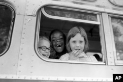 FILE - Children smile from the window of a school bus in Springfield, Mass., as court-ordered busing brought Black children and white children together in elementary grades without incident, Sept. 16, 1974. (AP Photo/Peter Bregg, File)