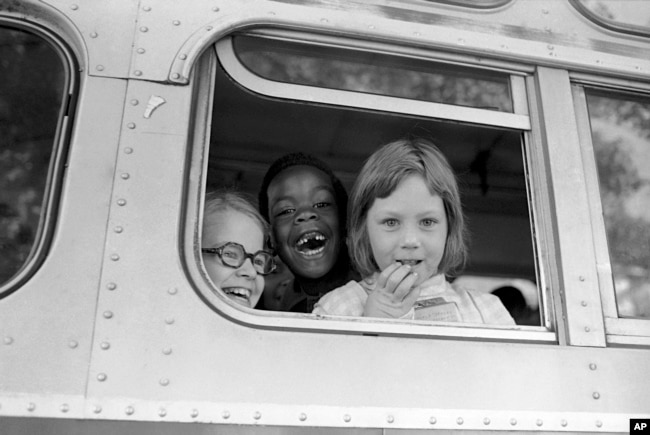 FILE - Children smile from the window of a school bus in Springfield, Mass., as court-ordered busing brought Black children and white children together in elementary grades without incident, Sept. 16, 1974. (AP Photo/Peter Bregg, File)