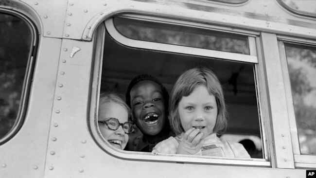 FILE - Children smile from the window of a school bus in Springfield, Mass., as court-ordered busing brought Black children and white children together in elementary grades without incident, Sept. 16, 1974. (AP Photo/Peter Bregg, File)