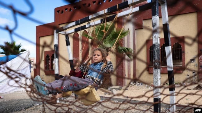 A displaced Palestinian girl sits on a swing in Rafah on May 15, 2024.