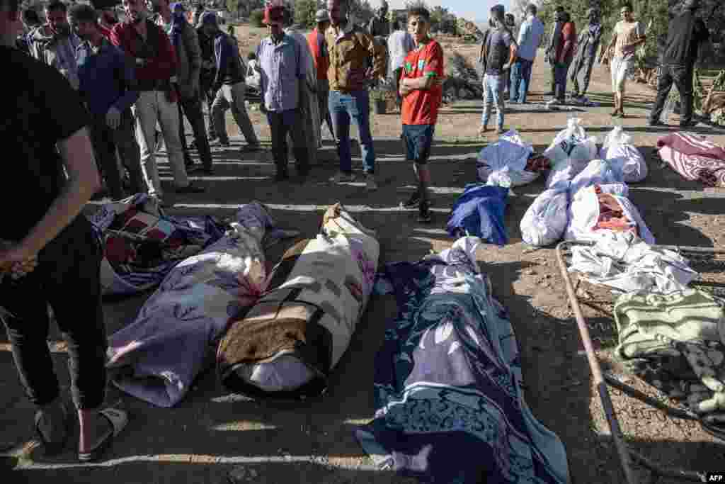 People gather around the bodies of victims of an earthquake in the mountain village of Tafeghaghte, southwest of the city of Marrakesh, Morocco, on Sept. 9, 2023. 