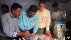 Los funcionarios electorales revisan y sellan una máquina de votación electrónica antes de permitir que los votantes emitan sus votos en un colegio electoral durante la última ronda de una elección nacional de seis semanas cerca de Dharamshala, India, el 1 de junio de 2024.