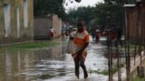 A person wades on a street flooded after heavy rainfall in Gatumba, Burundi