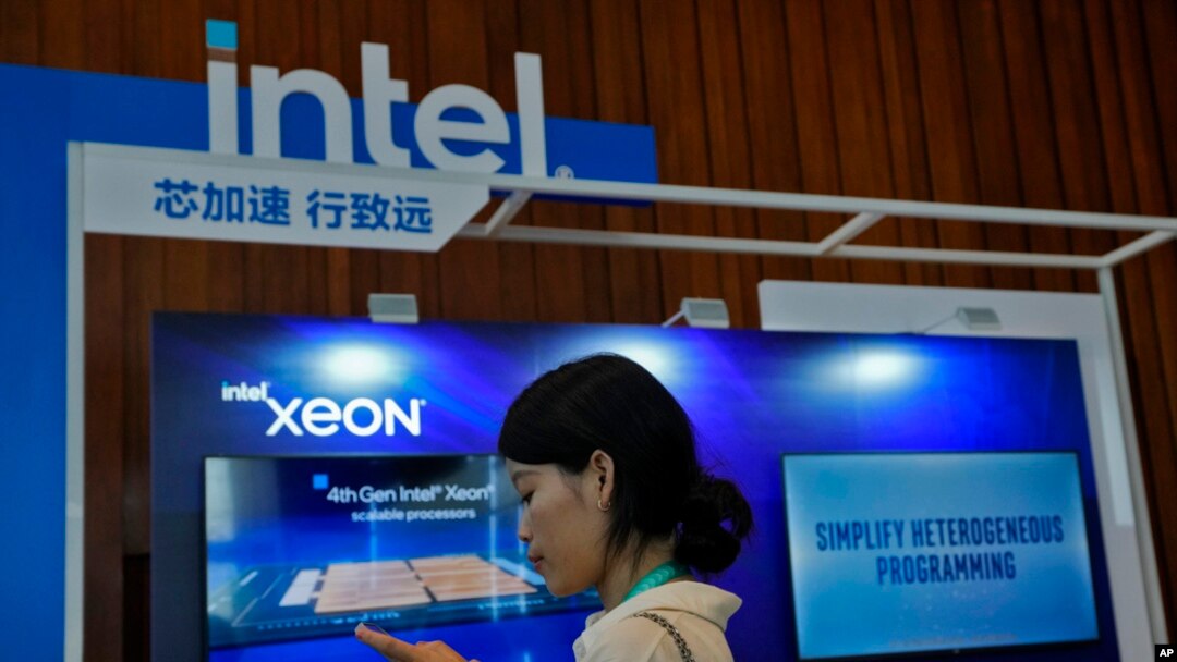 FILE - A woman checks her smartphone near an Intel booth promoting Xeon chips during a tech summit in Beijing, Aug. 16, 2023. China will phase out use of microprocessors from Intel and AMD, the Financial Times reported March 24, 2024. 