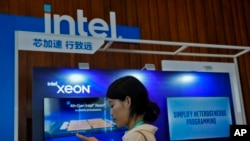 FILE - A woman checks her smartphone near an Intel booth promoting Xeon chips during a tech summit in Beijing, Aug. 16, 2023. China will phase out use of microprocessors from Intel and AMD, the Financial Times reported March 24, 2024. 