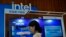 FILE - A woman checks her smartphone near an Intel booth promoting Xeon chips during a tech summit in Beijing, Aug. 16, 2023. 