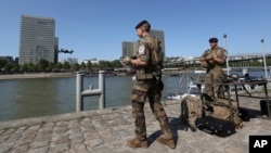 A French soldier pilots a drone over the Seine river as another looks on, in Paris, July 17, 2024.