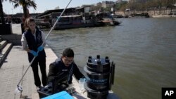 Senior technician Omar Bach-Rais testes water samples from the River Seine for analysis as Aurelie Lemaire, a microbiology research intern looks on, in Paris, April 5, 2023.