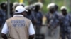 Foto ilustrasi yang menunjukkan seorang jurnalis melihat ke arah pasukan kemananan yang berjaga dalam sebuah aksi protes di Lome, Togo, pada 19 Februari 2013. (Foto: AFP/Daniel Hayduk)