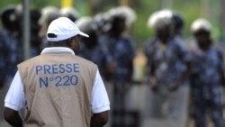 Foto ilustrasi yang menunjukkan seorang jurnalis melihat ke arah pasukan kemananan yang berjaga dalam sebuah aksi protes di Lome, Togo, pada 19 Februari 2013. (Foto: AFP/Daniel Hayduk)