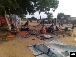 FILE - Residents displaced from a surge of violent attacks squat on blankets and in hastily made tents in the village of Masteri in west Darfur, Sudan, on July 30, 2020.