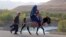 Seorang perempuan Afghanistan mengenakan burqa dengan anak-anaknya mengendarai keledai di distrik Kishim, provinsi Badakhshan. (AFP)&nbsp;