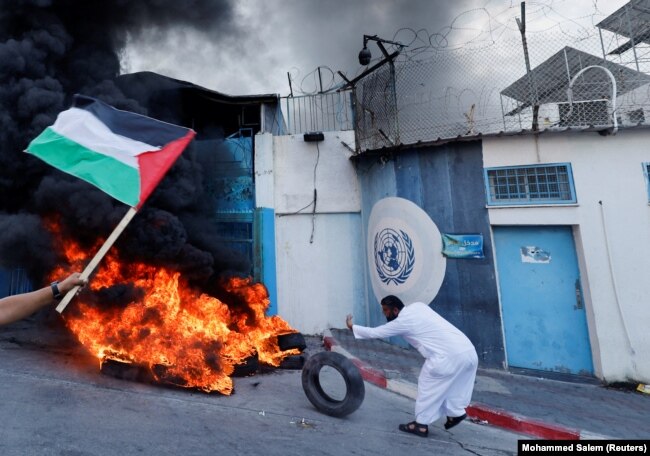 Seorang pria Palestina membakar ban di luar markas UNRWA yang menuntut UNRWA untuk membangun kembali rumah mereka yang hancur selama pertempuran Israel-Gaza pada 2014, di Kota Gaza, 19 September 2022. (Foto: REUTERS/Mohammed Salem)