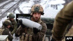 A Ukrainian artilleryman of the Aidar battalion holds an artillery shell on a front line position near Bakhmut, Donetsk region, on April 22, 2023.