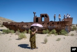 People visit rusted ships near a museum, outside Muynak, Uzbekistan, July 14, 2023.
