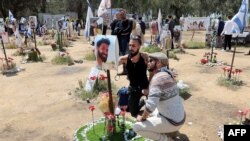 FILE - Israelis visit a memorial bearing portraits of people taken hostage or killed in the Hamas attack on the Supernova music festival on Oct. 7 at the site of the festival near Kibbutz Reim in southern Israel on April 10, 2024. 