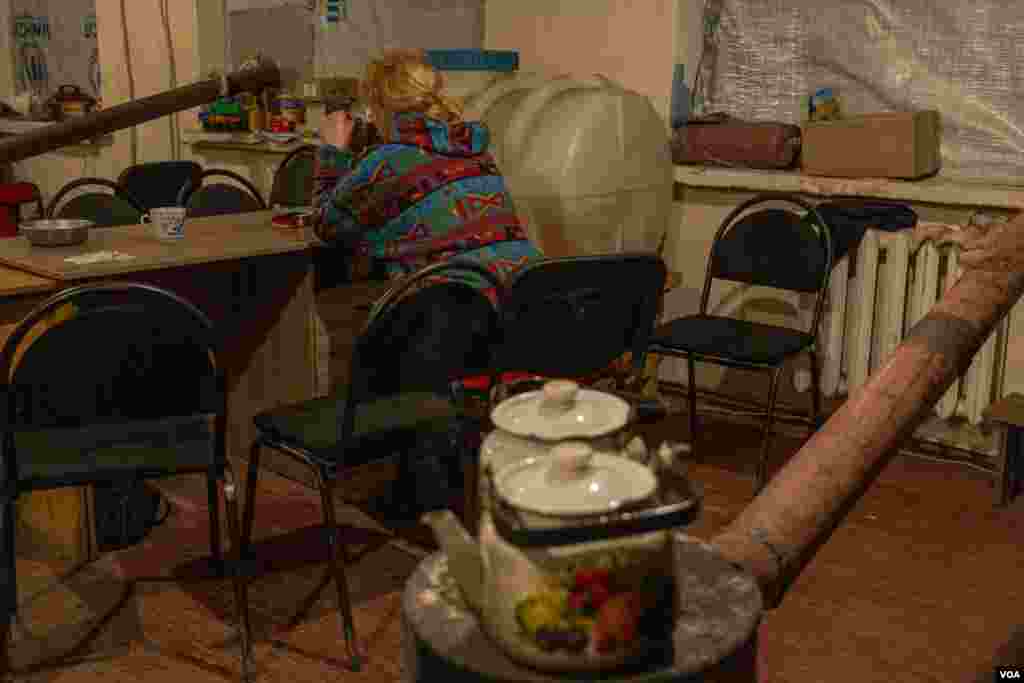 A woman drinks tea at the only shelter still open in Chasiv Yar, Ukraine, close to the front lines in Bakhmut, on April 12, 2023. (Yan Boechat/VOA) 