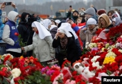 People lay flowers at a makeshift memorial to the victims of a shooting attack set up outside the Crocus City Hall concert venue in the Moscow Region, Russia, March 24, 2024.