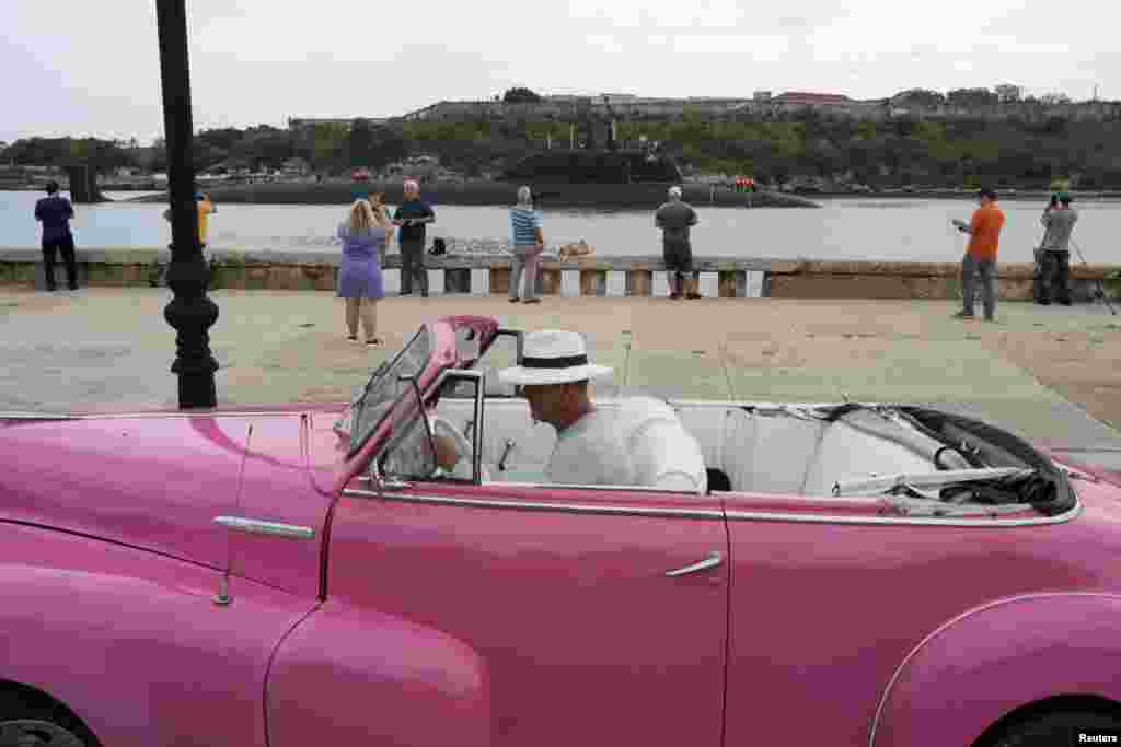 A driver parks a vintage car as Russian nuclear-powered cruise missile submarine Kazan enters Havana&rsquo;s bay, Cuba.
