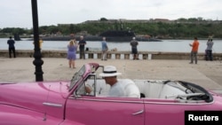 A driver parks a vintage car as Russian nuclear-powered cruise missile submarine Kazan enters Havana&rsquo;s bay, Cuba.