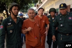 FILE - Yi Soksan (C left) and Ny Sokha (2nd R), both Cambodian senior officers from The Cambodian Human Rights and Development Association (ADHOC), are escorted by police officials outside the appeals court in Phnom Penh on August 30, 2016.