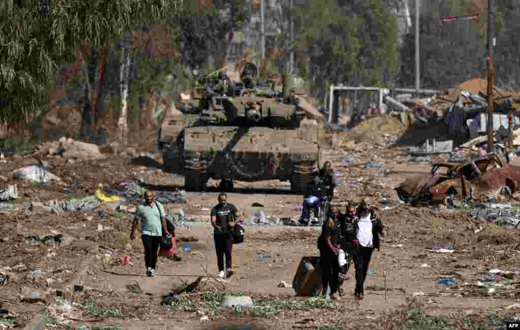 Palestinians fleeing the north through the Salaheddine road in the Zeitoun district on the southern outskirts of Gaza City, walk past Israeli army tanks, Nov. 24, 2023, following a four-day ceasefire that began early in the morning.