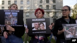 民众手举被巴勒斯坦武装分子杀害和劫为人质的以色列妇女与儿童的照片在伦敦的英国首相官邸唐宁街10号外举行支持以色列的集会。（2023年10月9日）