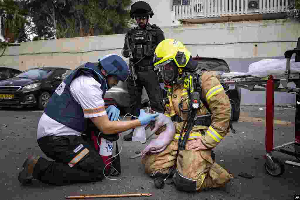 A firefighter and a paramedic deliver oxygen to an injured cat rescued from a building struck by a rocket fired from Gaza, in Tel Aviv, Israel.