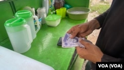 Andry Araque, vendedor de cocos en Maracaibo, repasa sus ganancias en bolívares y dólares la mañana de este miércoles. Como el resto de los comerciantes informales, fija sus precios según la fluctuación del dólar estadounidense.